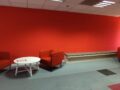 Zona de descanso con pared roja e iluminación LED en las oficinas de Save the Children en Madrid, reformadas por Buenos Días Buenas Noches